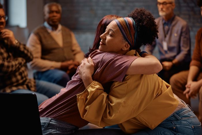 A support group member receiving a hug