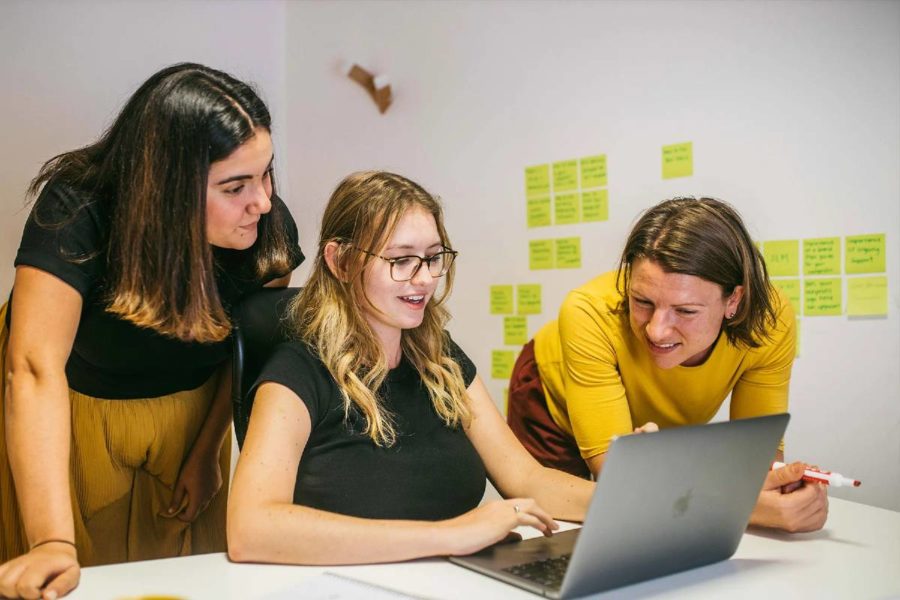 Marie, Sarah and Emily from our team collaborating around a computer