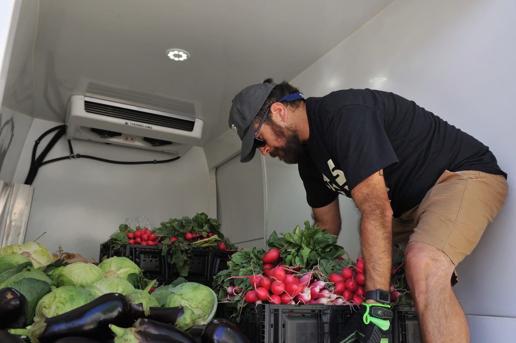 A Second Harvest volunteer loading fresh produce into a mobile food pantry