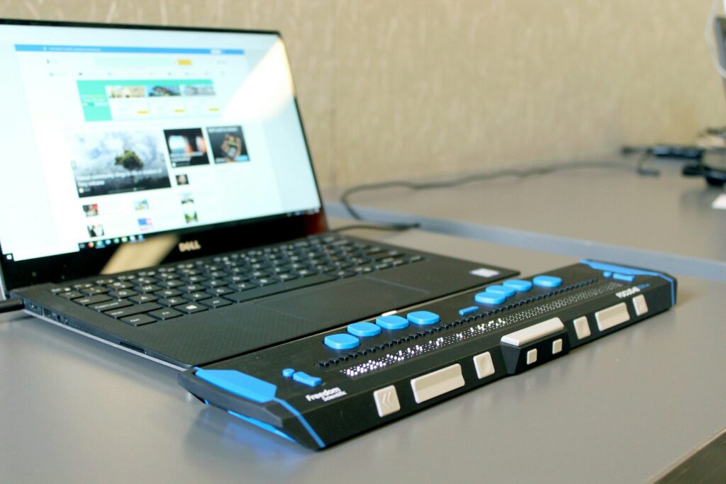 Laptop on a desk connected to a refreshable braille display