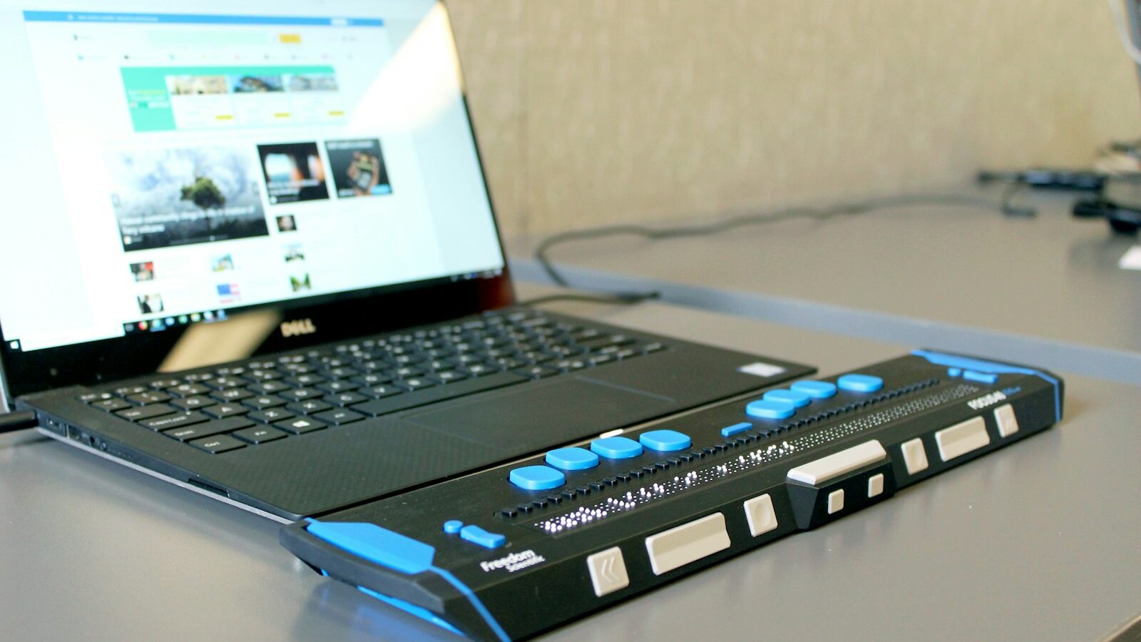 Laptop on a desk connected to a refreshable braille display