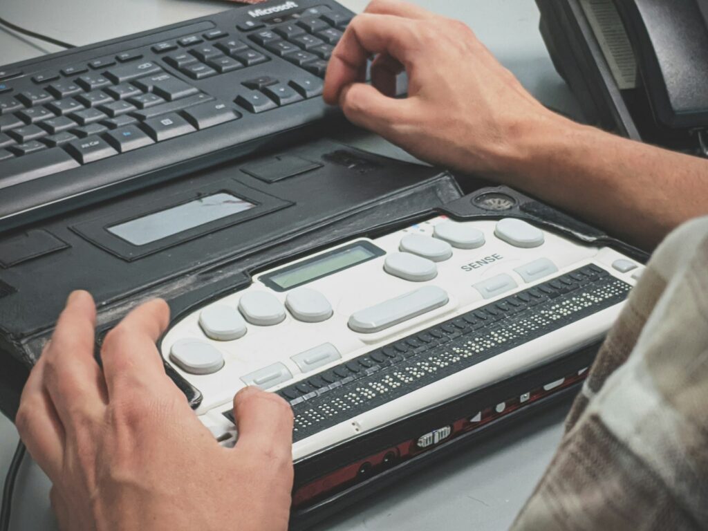Hands reading a refreshable braille display next to a keyboard