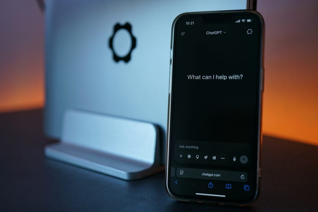 Phone showing the ChatGPT app in front of a laptop