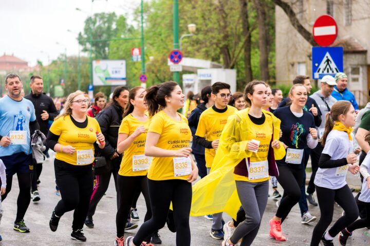 Participants in matching yellow shirts running a charity race on a city street